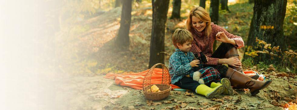 woman and child sitting in forest enjoying picnic