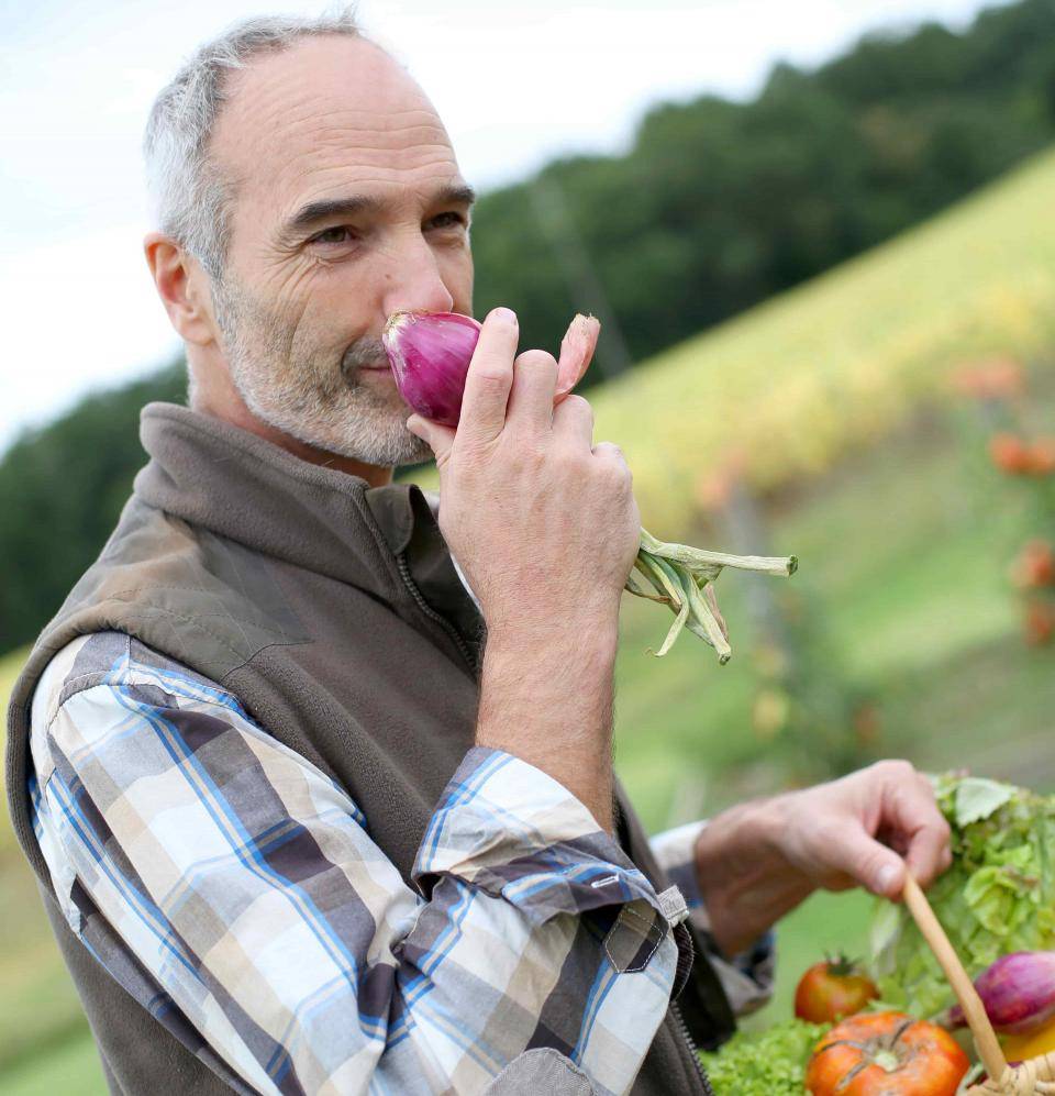 Middle aged man smiling and smelling fresh vegetables