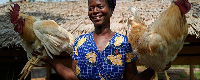 Empower the women Esther holding two roosters from her own farm 